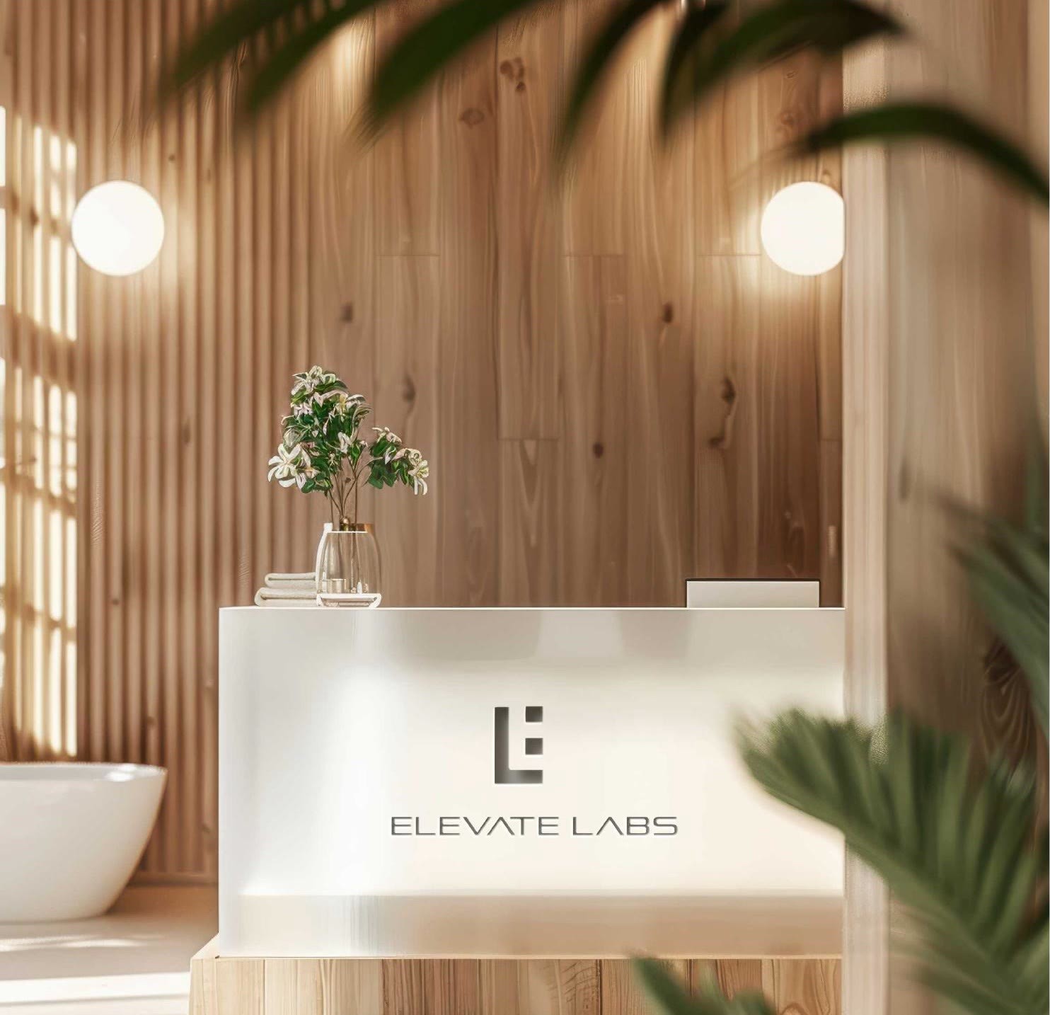 Reception of the biohacking clinic with Elevate Labs branding, warm timber and plants