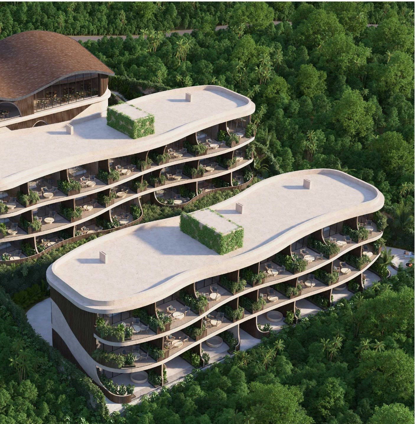 Aerial view of Luma — two residence blocks and the wellness center set into dense jungle above the Uluwatu coastline